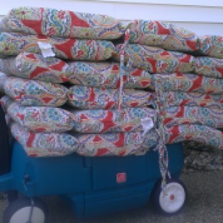 Here's a neat trick for storing cushions. Stack them on a kid's wagon and cover with a grill cover all summer to keep them near the table. During the off-season I plan to wheel them into the garage for storage.